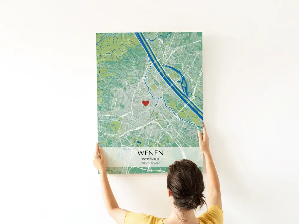 Groen-blauwe stadskaartposter met hartje en coördinaten op een lichte tekstbalk, tegen een witte muur