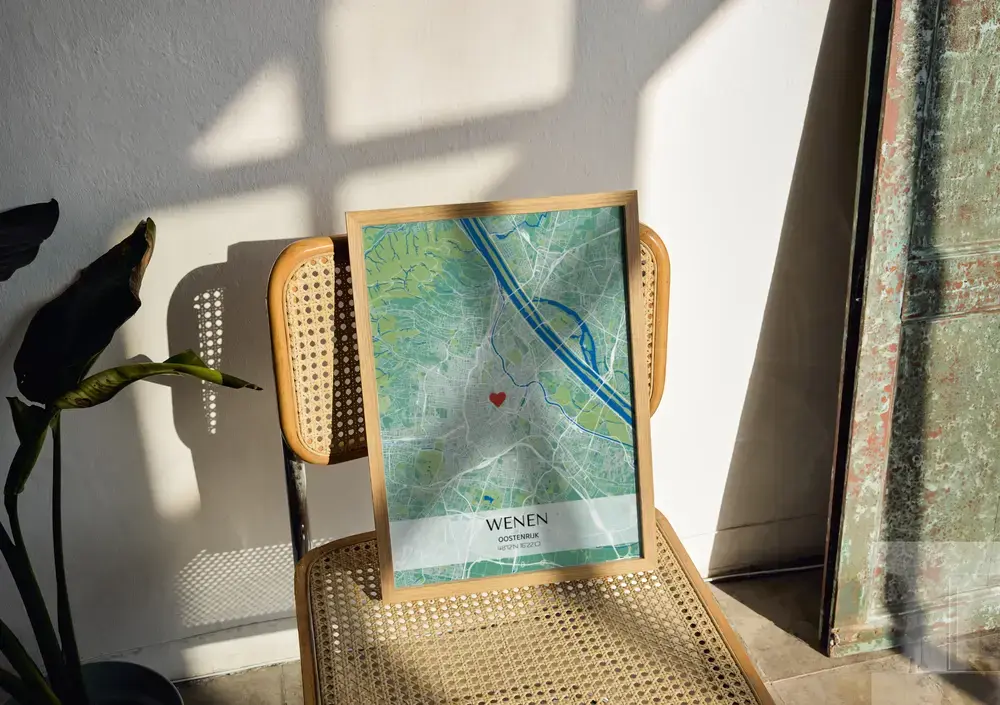Groen-blauwe stadskaartposter met coördinaten in een houten lijst, op een stoel met webbing in het zonlicht